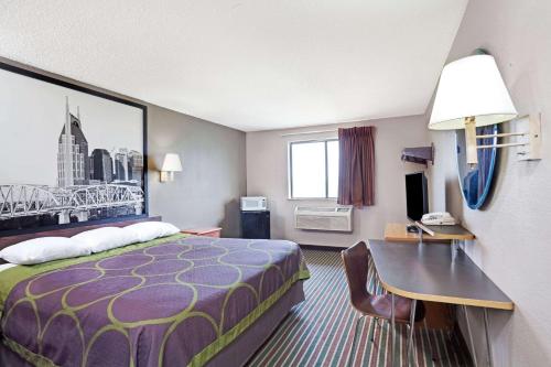a small hotel room with a bed and a desk at Super 8 by Wyndham Nashville/ Dntn/ Opryland Area in Nashville
