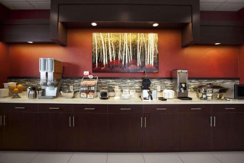 a kitchen with brown cabinets and a painting on the wall at Super 8 by Wyndham Conrad in Conrad