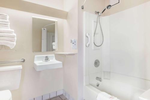 baño blanco con ducha y lavamanos en Super 8 by Wyndham Dodge City, en Dodge City