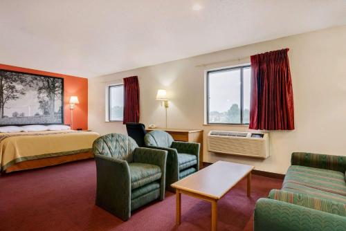 a hotel room with a bed and chairs at Hillside Inn & Suite in Martinsburg