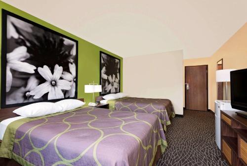 a hotel room with two beds and a flat screen tv at Super 8 by Wyndham Muncie/Ball St. College Area in Muncie