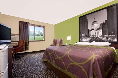 a hotel room with a large bed and a desk at Super 8 by Wyndham Muncie/Ball St. College Area in Muncie