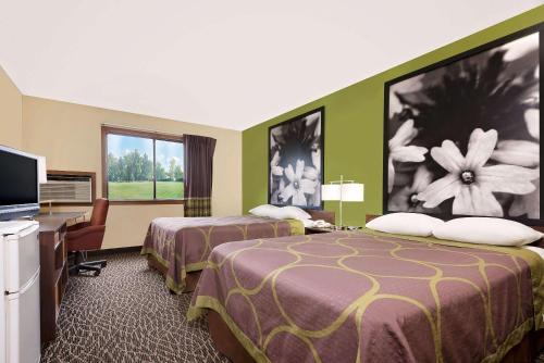 a hotel room with two beds and a flat screen tv at Super 8 by Wyndham Muncie/Ball St. College Area in Muncie