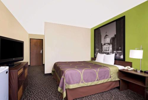 a hotel room with a bed and a flat screen tv at Super 8 by Wyndham Muncie/Ball St. College Area in Muncie