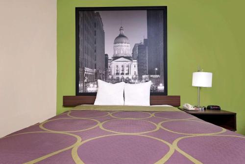 a bedroom with a bed with a picture of a building at Super 8 by Wyndham Muncie/Ball St. College Area in Muncie