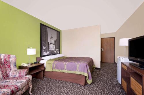 a hotel room with a bed and a couch at Super 8 by Wyndham Muncie/Ball St. College Area in Muncie