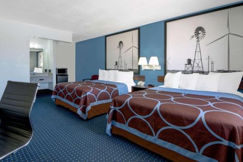 two beds in a hotel room with blue walls at Super 8 by Wyndham Dumas TX in Dumas