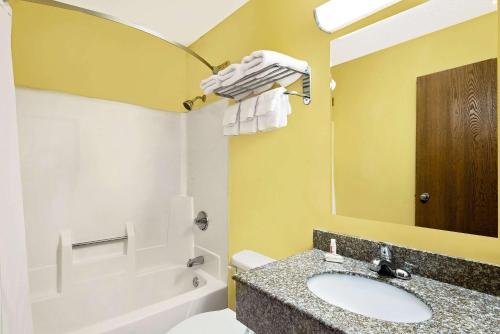 a bathroom with a sink and a toilet and a mirror at Super 8 by Wyndham Muncie/Ball St. College Area in Muncie