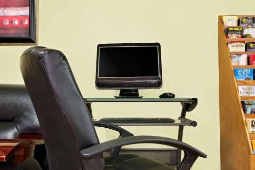 a computer monitor sitting on a desk with a chair at Super 8 by Wyndham Muncie/Ball St. College Area in Muncie