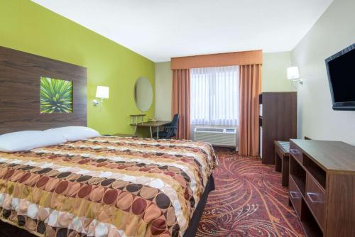 a hotel room with a bed and a flat screen tv at Super 8 by Wyndham Portales in Portales