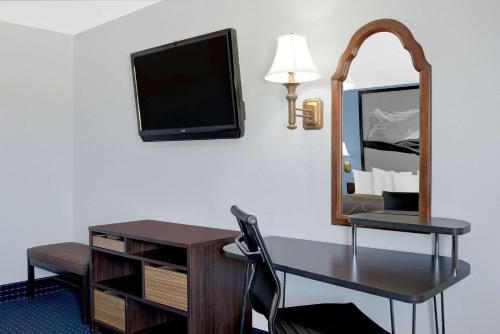 a room with a desk and a tv and a mirror at Super 8 by Wyndham Dumas TX in Dumas