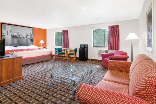 a hotel room with a bed and a living room at Super 8 by Wyndham Kent/Akron Area in Kent