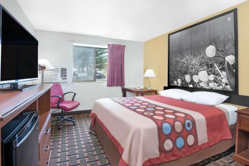 a hotel room with a bed and a flat screen tv at Super 8 by Wyndham Kent/Akron Area in Kent