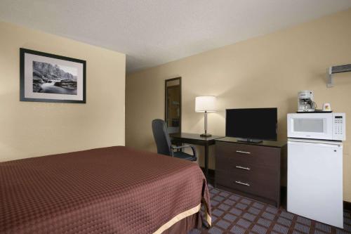 サギノーにあるSuper 8 by Wyndham Saginawのベッドと机とテレビがあるホテルの部屋