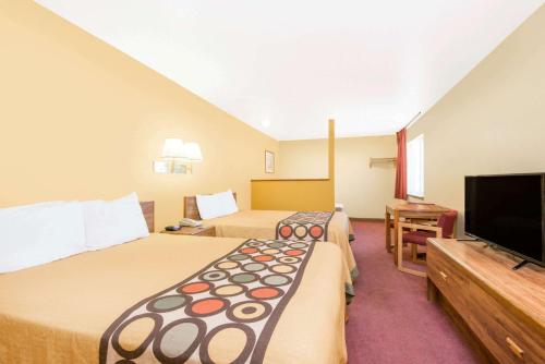 a hotel room with two beds and a flat screen tv at Super 8 by Wyndham Moriarty in Moriarty