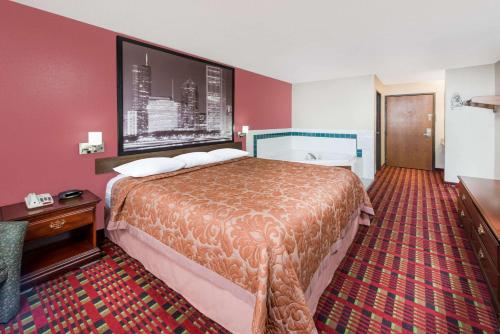 a hotel room with a large bed and a red wall at Super 8 by Wyndham Paris IL in Paris