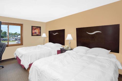 a hotel room with two beds with white sheets at Super 8 by Wyndham Sheboygan WI in Sheboygan