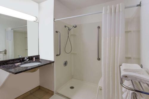 a white bathroom with a shower and a sink at Super 8 by Wyndham Janesville in Janesville