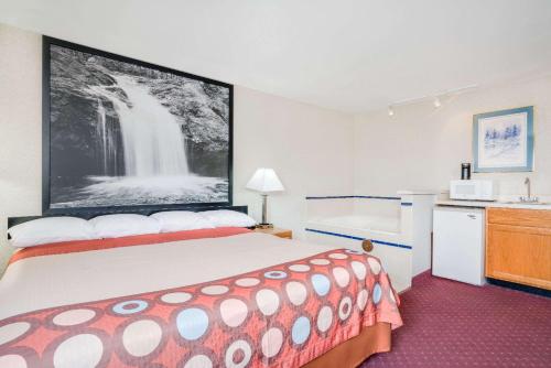 a hotel room with a bed and a waterfall on the wall at Super 8 by Wyndham Tomah Wisconsin in Tomah