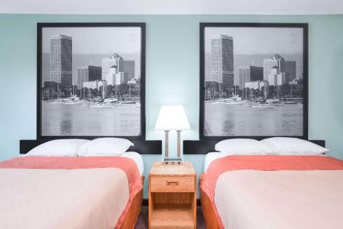 two beds in a room with two posters on the wall at Super 8 by Wyndham Tomah Wisconsin in Tomah