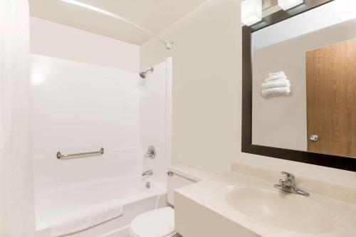 een witte badkamer met een wastafel en een spiegel bij Super 8 by Wyndham Ames in Ames