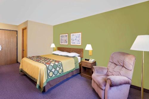 a hotel room with a bed and a chair at Super 8 by Wyndham Dyersville in Dyersville