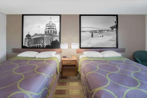 two beds in a hotel room with pictures on the wall at Super 8 by Wyndham Toledo in Toledo