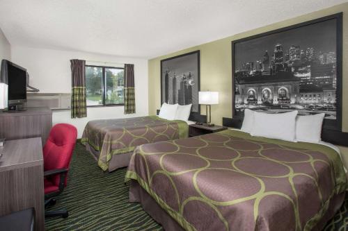 una habitación de hotel con 2 camas y una silla roja en Super 8 by Wyndham Independence Kansas City, en Independence