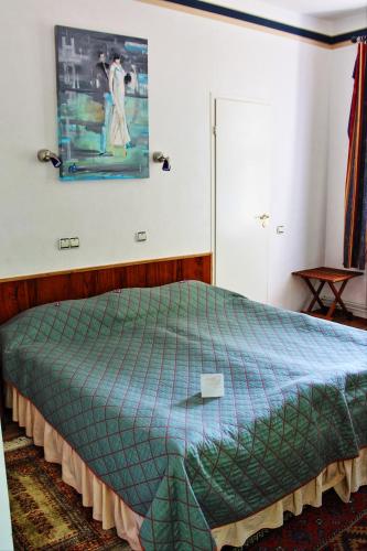 a bedroom with a bed with a green comforter at NB Hotel with Free Parking in Rīga