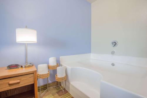 a bathroom with a tub and a table with a lamp at Super 8 by Wyndham Toledo in Toledo