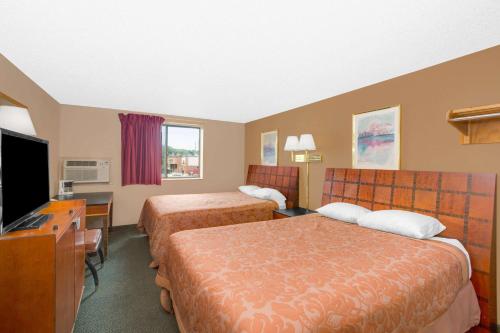 a hotel room with two beds and a flat screen tv at Super 8 by Wyndham Sioux City/Morningside Area in Sioux City