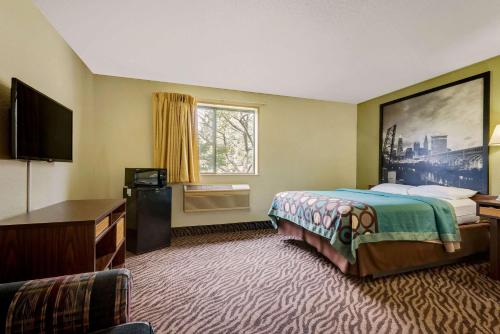 a hotel room with a bed and a flat screen tv at Super 8 by Wyndham Mentor/Cleveland Area in Mentor