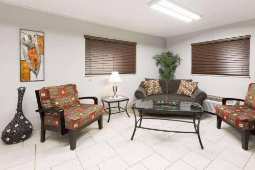 a living room with a couch and chairs and a guitar at Super 8 by Wyndham Osceola IA in Osceola