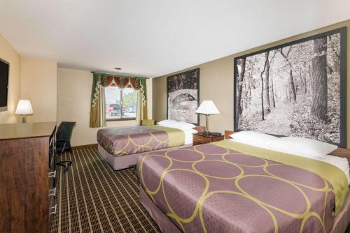 a hotel room with two beds and a flat screen tv at Super 8 by Wyndham Webster City IA in Webster City