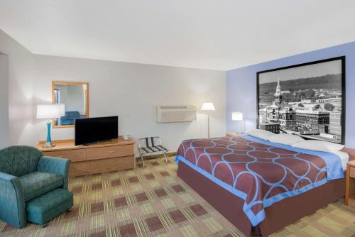 a hotel room with a bed and a chair at Super 8 by Wyndham Toledo in Toledo
