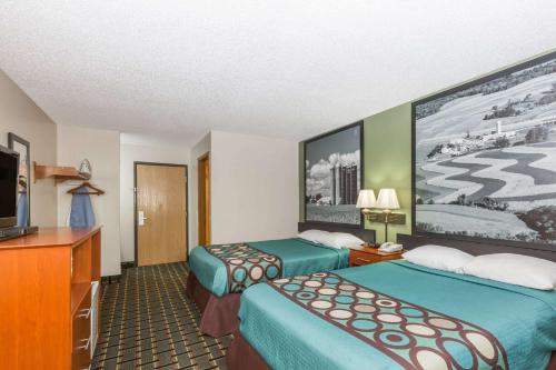 a hotel room with two beds and a flat screen tv at Super 8 by Wyndham Osceola IA in Osceola