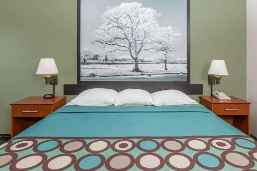 a bedroom with a bed with two lamps and a tree at Super 8 by Wyndham Osceola IA in Osceola