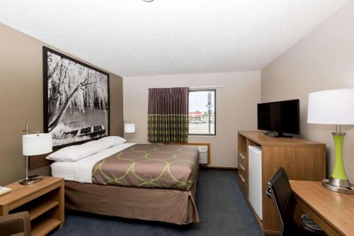 ein Hotelzimmer mit einem Bett und einem Flachbild-TV in der Unterkunft Super 8 by Wyndham Hays KS in Hays