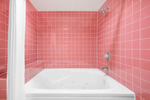 Baño de azulejos rojos con bañera blanca. en Super 8 by Wyndham Story City, en Story City