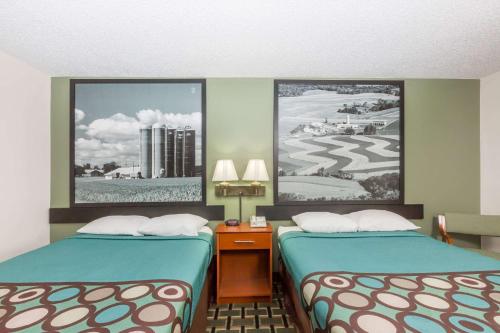 a room with two beds and two pictures on the wall at Super 8 by Wyndham Osceola IA in Osceola