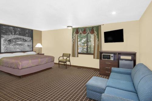 a hotel room with a bed and a couch and a tv at Super 8 by Wyndham Webster City IA in Webster City