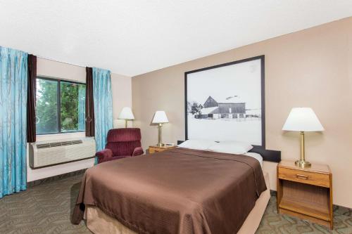 a hotel room with a bed and a chair and a window at Super 8 by Wyndham Dodgeville in Dodgeville