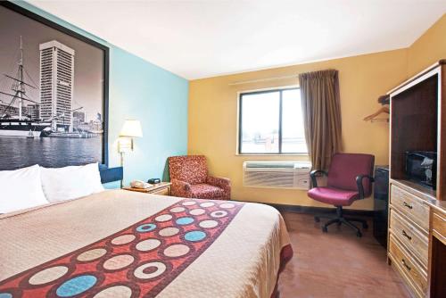 a hotel room with a bed and a chair and a window at Super 8 by Wyndham Baltimore/Essex Area in Essex