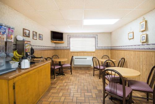 a dining room with tables and chairs and a kitchen at Super 8 by Wyndham Nevada in Nevada