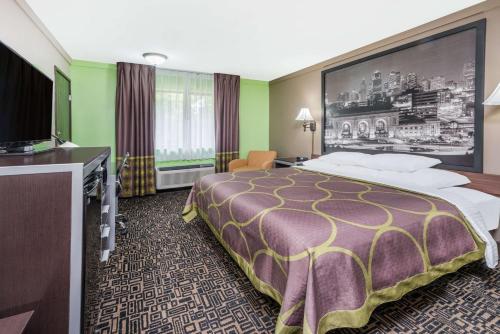 a hotel room with a bed and a flat screen tv at Super 8 by Wyndham Warrensburg in Warrensburg