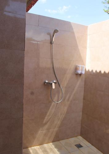 a shower with a shower head on a wall at Tunjung Kuning Cottage in Nusa Penida