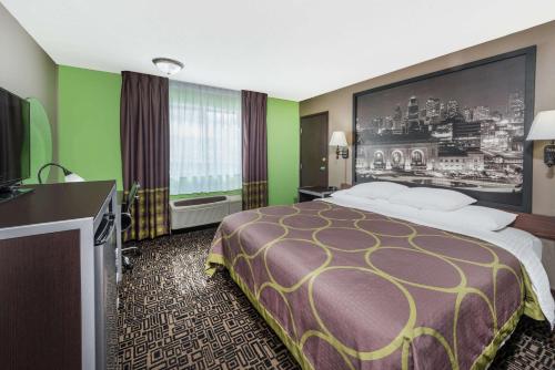 a hotel room with a bed and a flat screen tv at Super 8 by Wyndham Warrensburg in Warrensburg