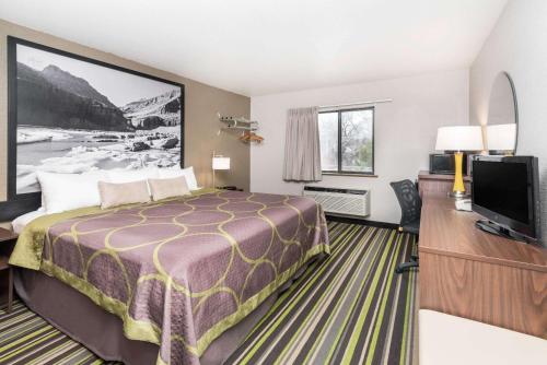 a hotel room with a bed and a flat screen tv at Super 8 by Wyndham Kalispell Glacier National Park in Kalispell