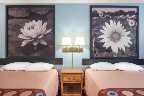 two beds in a room with two pictures on the wall at Super 8 by Wyndham Thurmont in Thurmont