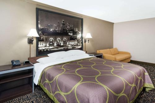 a hotel room with a large bed and a chair at Super 8 by Wyndham Warrensburg in Warrensburg